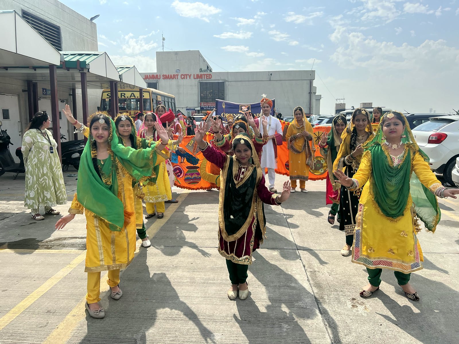 Girls in yellow and green Dogra suits dancing along the road