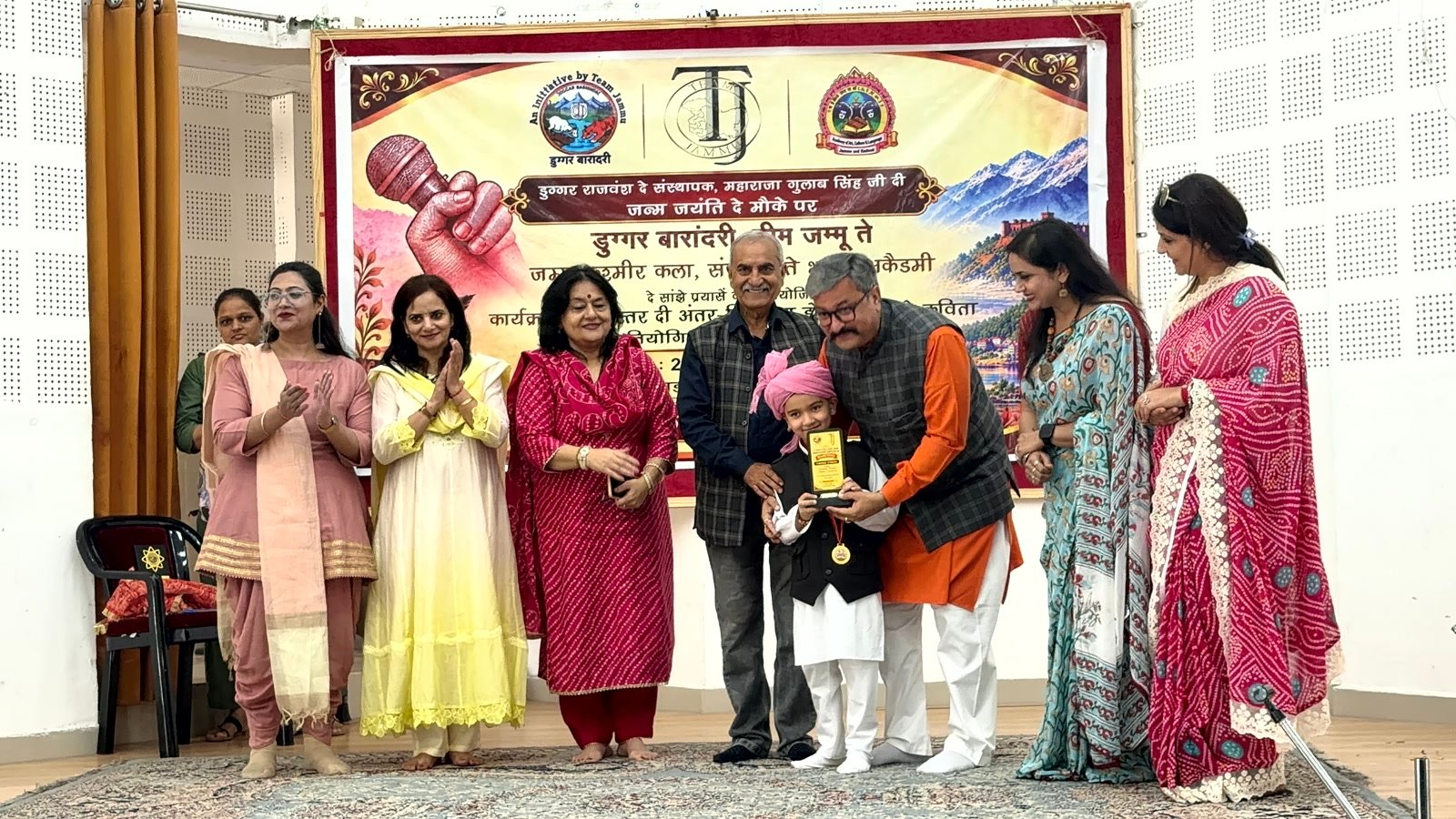 Shivansh Sharma of Senior KG, in a pink turban, receiving his trophy from the guests on stage