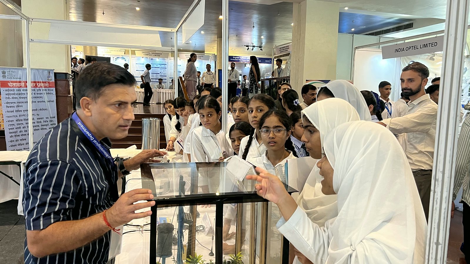 An exhibitor explaining a working model in a glass case to a group of Oriental Academy students