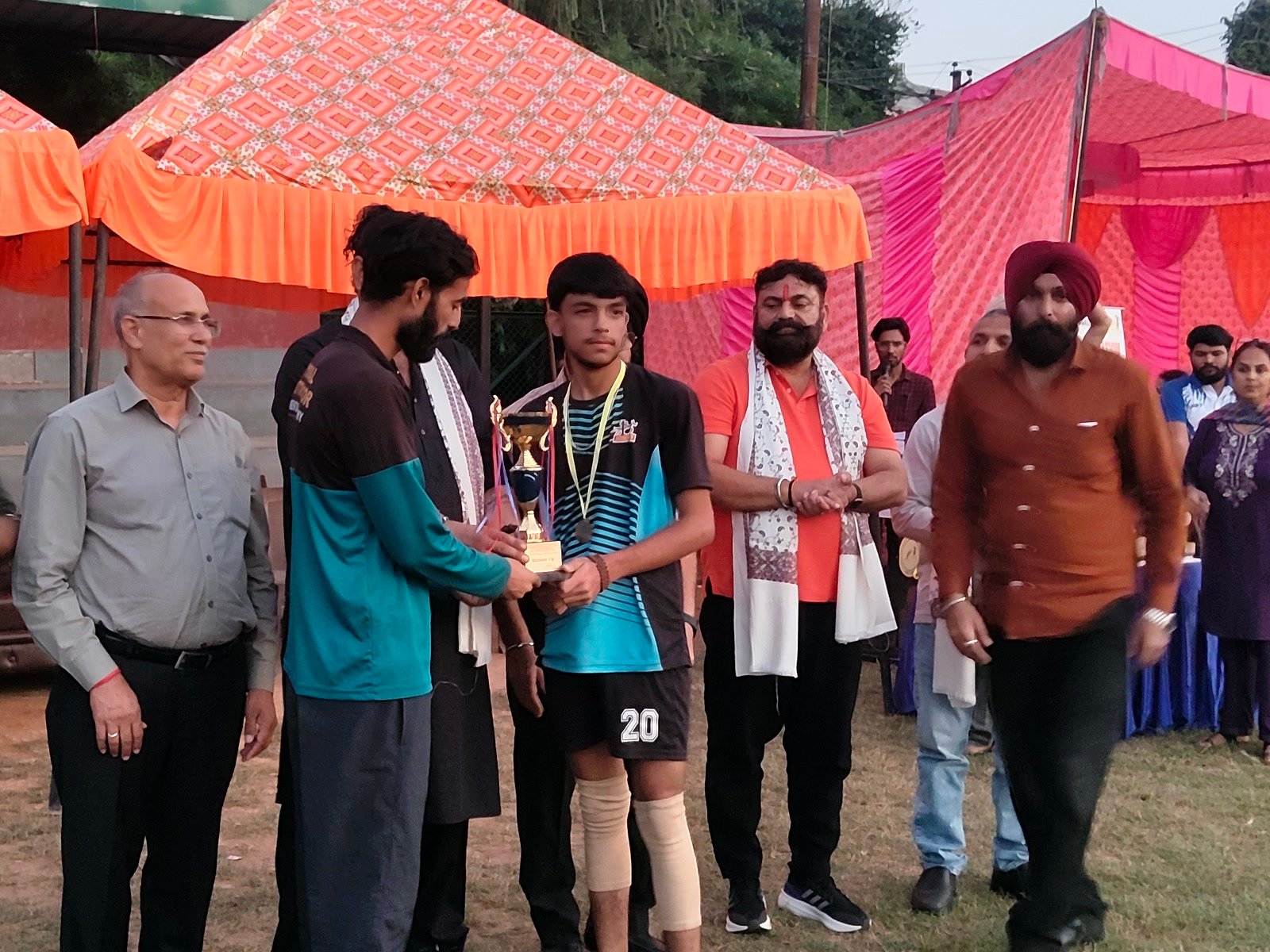 Boys' captain Krish, wearing his medal, receiving the runners-up trophy on the field