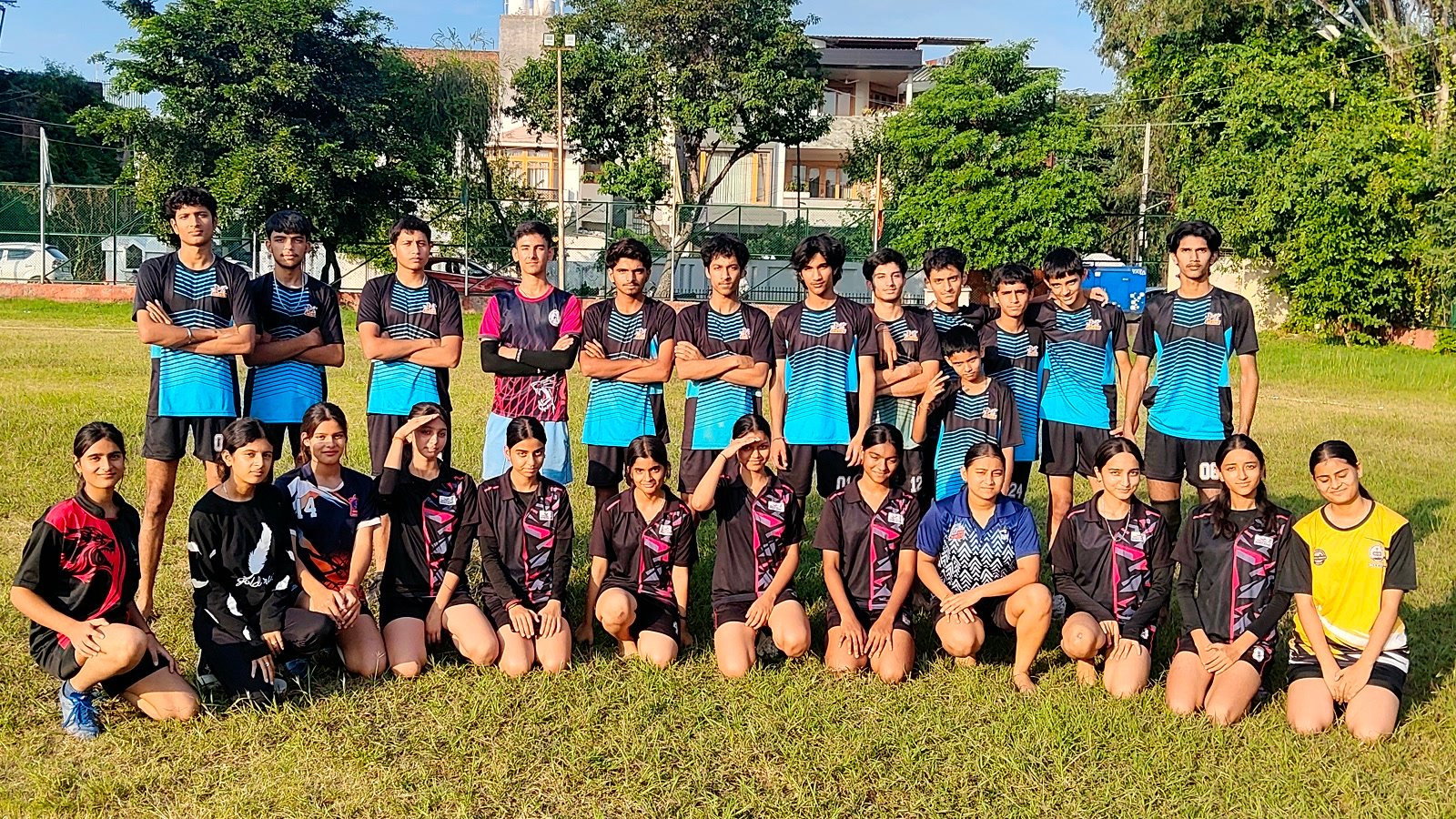Oriental Academy's boys' and girls' Kho-Kho teams in their kit on the grass at the Green Play Field, Gandhi Nagar