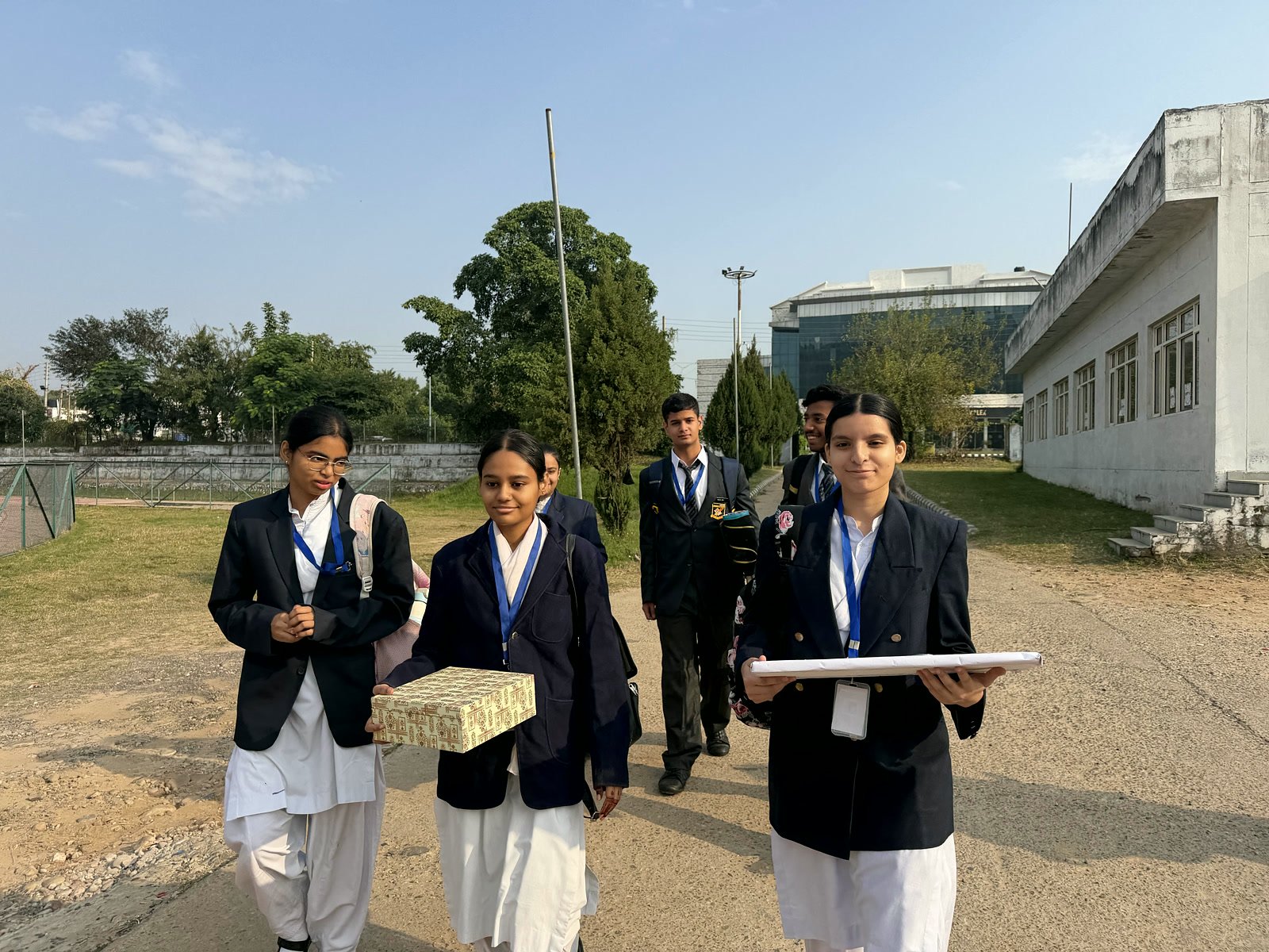 Oriental Academy students walking across the University of Jammu campus in the morning, carrying their project boxes
