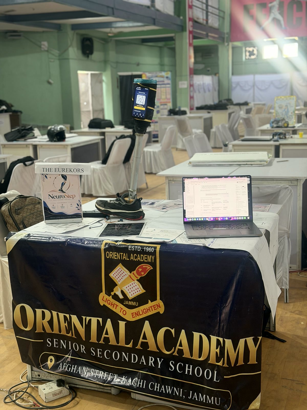 The NeuroStep stall: a prosthetic leg model with a phone attached, a laptop, and the Oriental Academy banner on the table