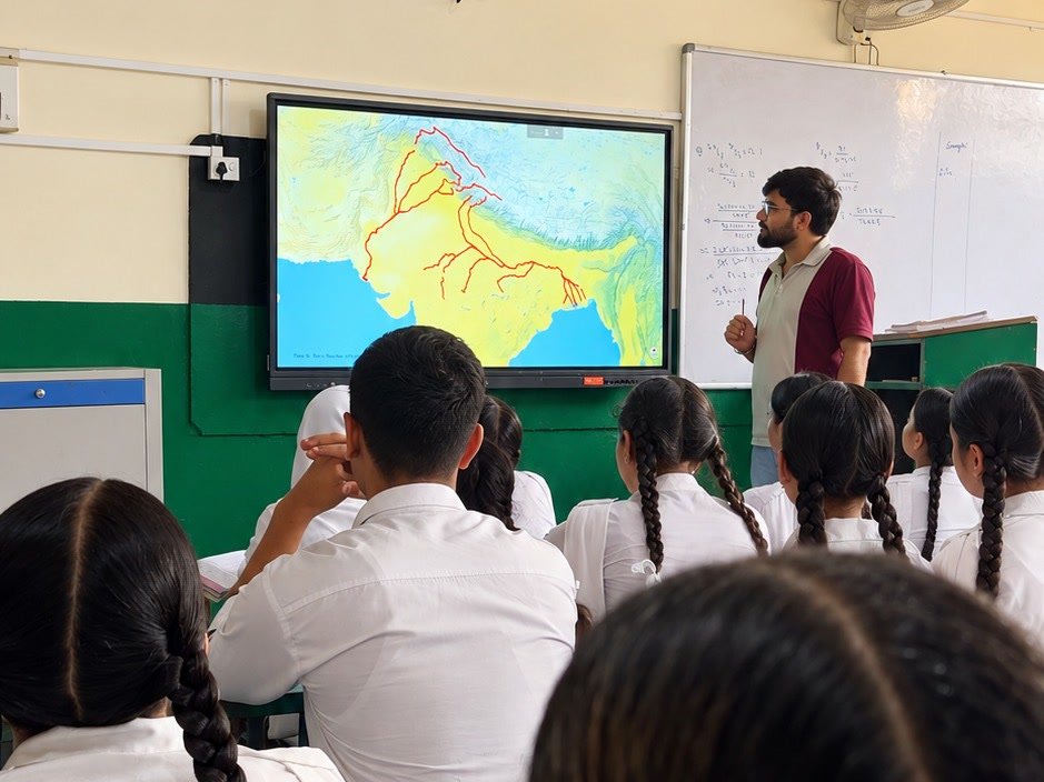 A teacher standing beside the smart board as a senior class follows a map of the rivers of north India