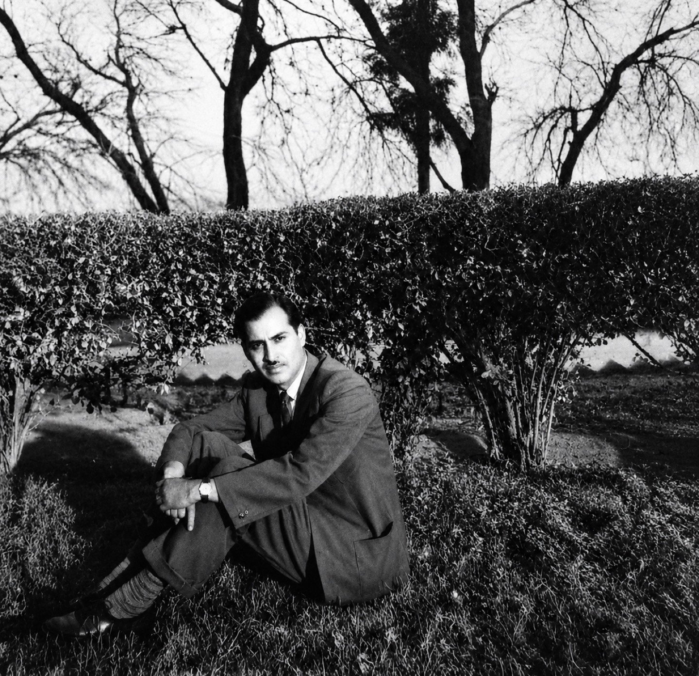 The founder, Late Sh. Ved Prakash Chauhan, as a young man, sitting on the grass beside a hedge