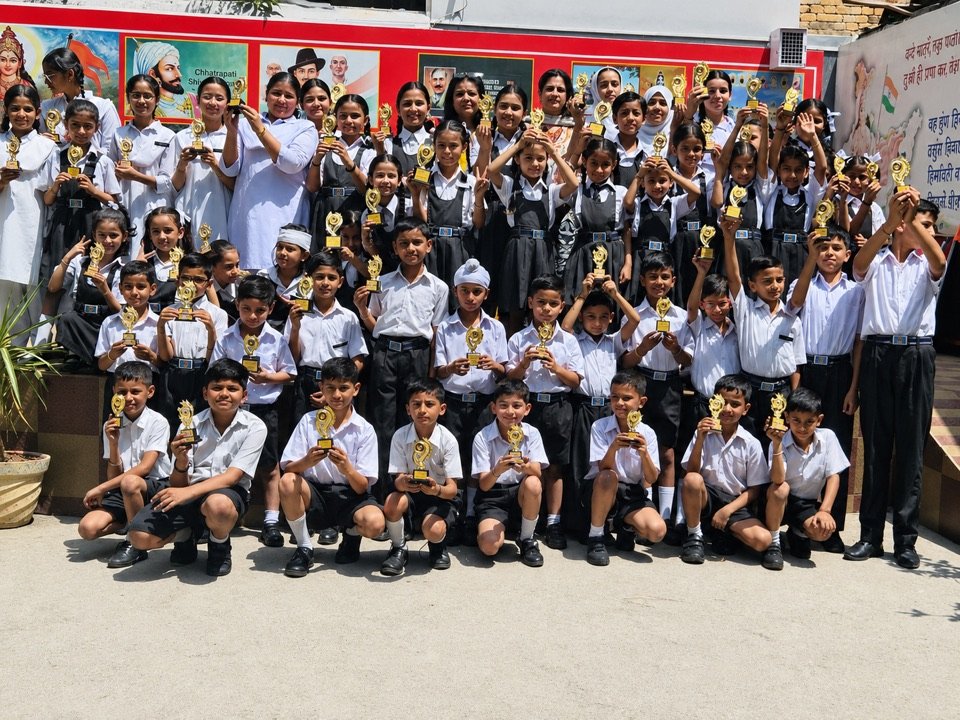 Prize distribution day at Oriental Academy: rows of children in uniform holding their trophies up high