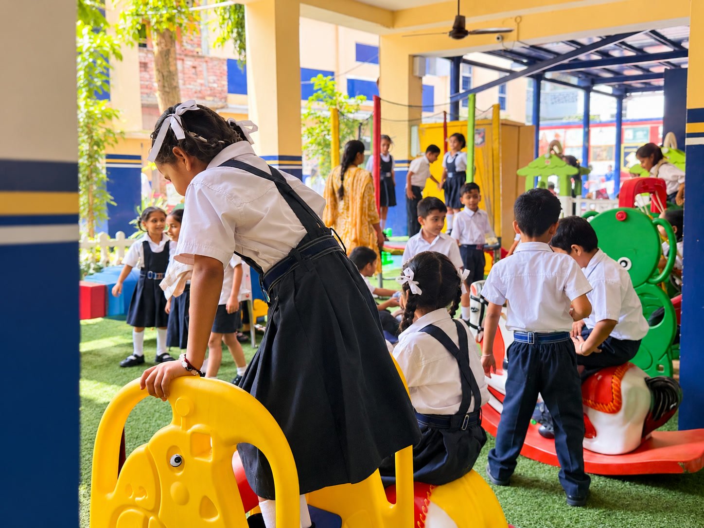 Junior children in uniform climbing on the rides in the covered play area during a break