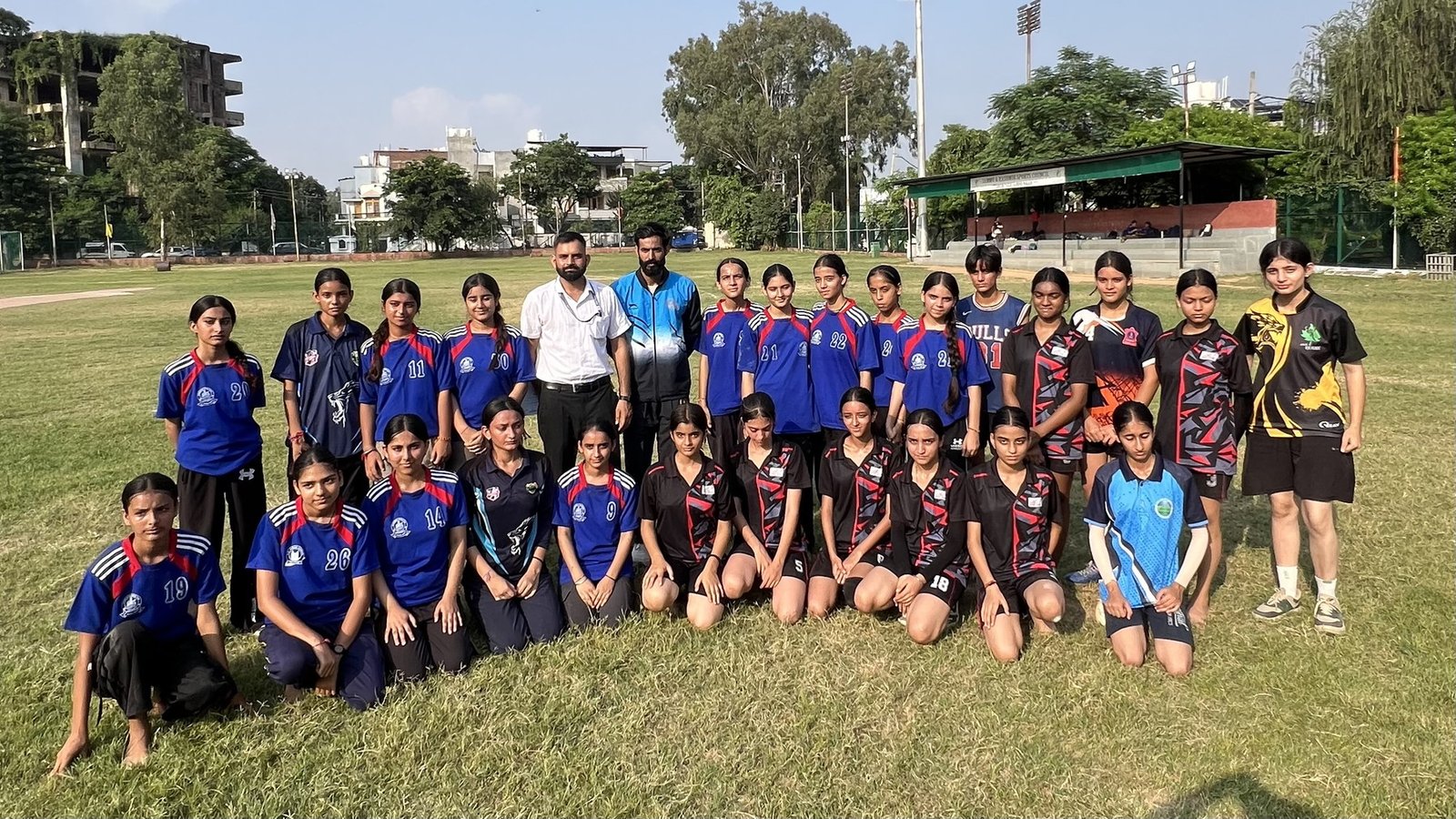 An Oriental Academy girls&rsquo; team with their coaches on the ground at the district championship