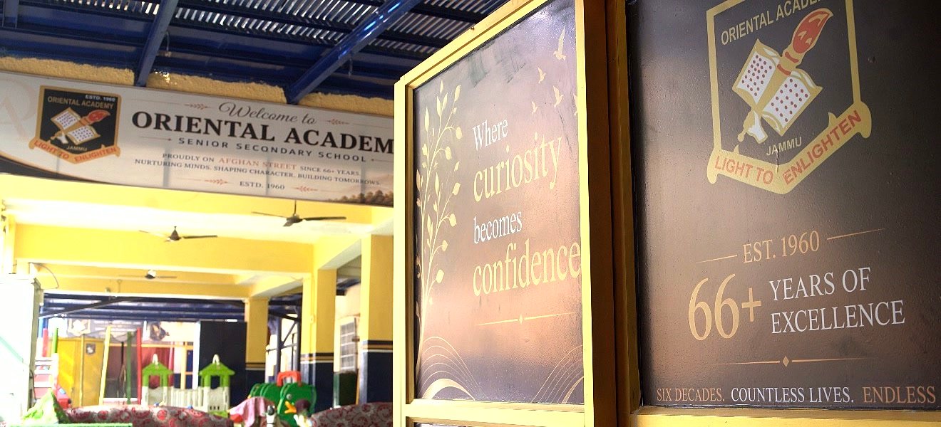 The entrance at Oriental Academy: a Welcome to Oriental Academy Senior Secondary School banner over the yellow verandah, a board reading Est. 1960, 66+ Years of Excellence, and the junior play area beyond