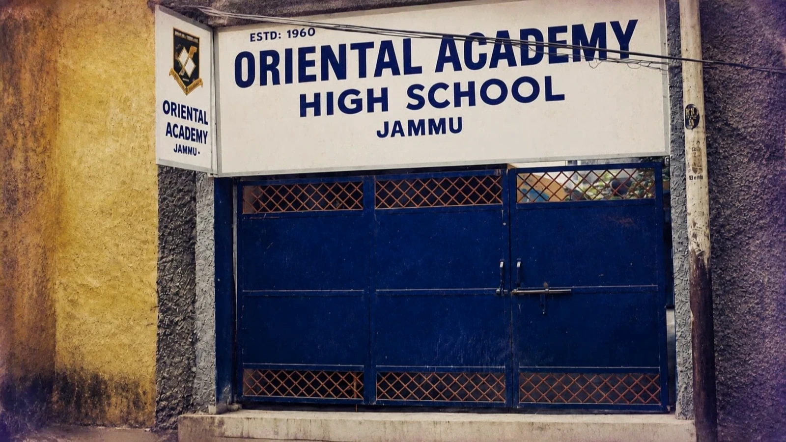 The old Oriental Academy gate, with its 'High School' signboard and plain blue gate, before the campus was renewed