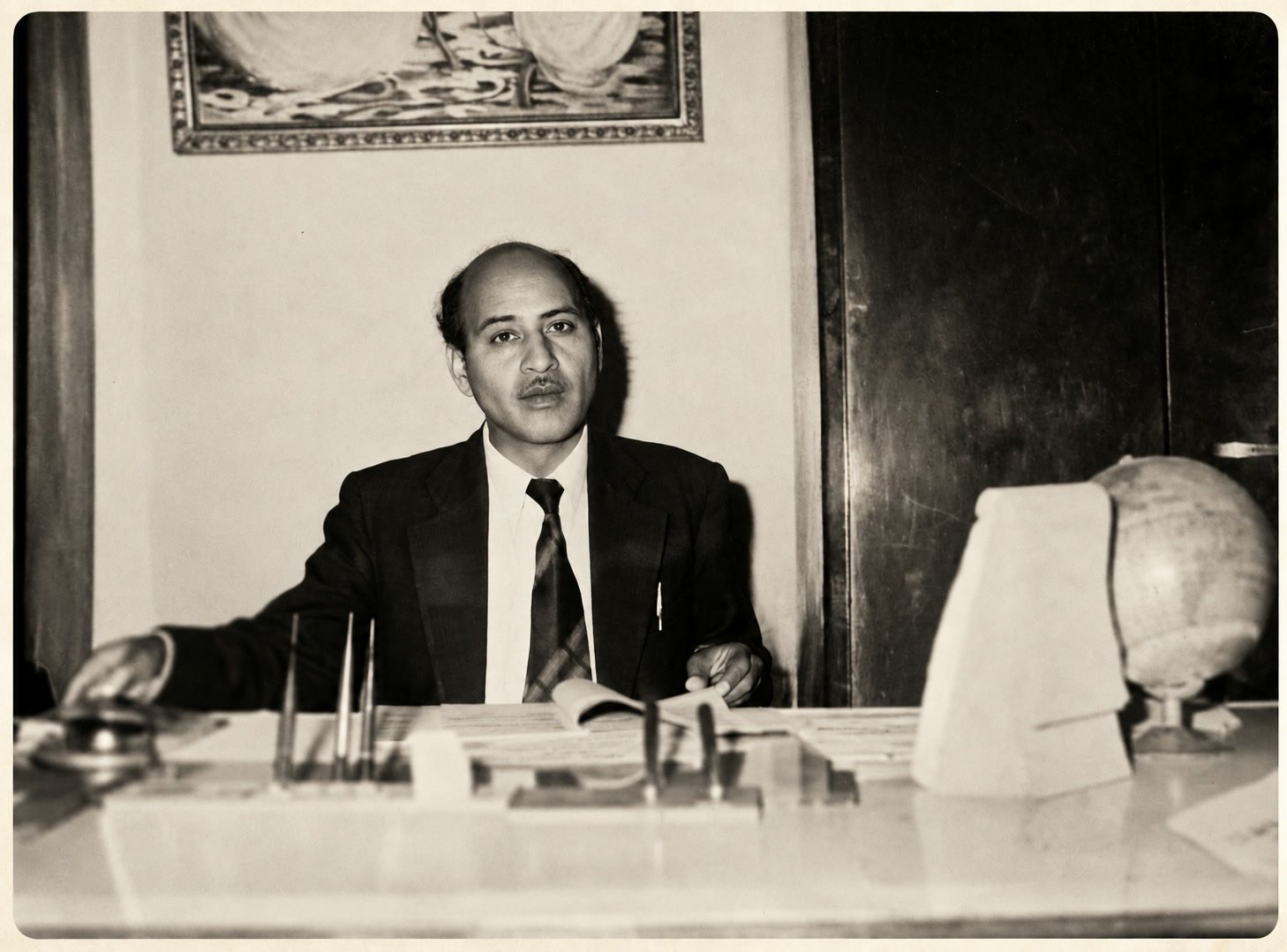 The founder, Late Sh. Ved Prakash Chauhan, seated at the desk of his first office, a globe on the desk beside him