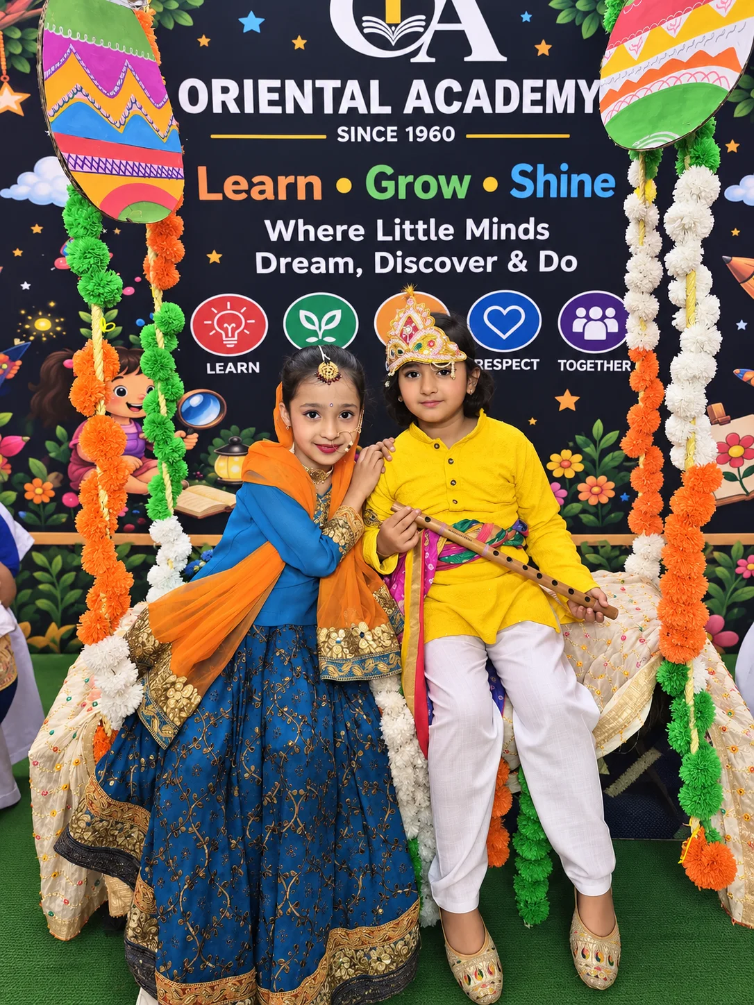 Two young Oriental Academy students dressed as Radha and Krishna on a decorated swing at the school's Janmashtami celebration